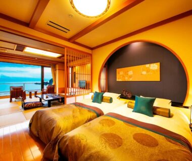 Twin beds in traditional Japanese room with tatami, low seating and coastal view at Yuhigauraonsen ShizukaHanaogi