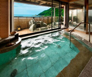 Indoor tiled onsen bath with glass wall and coastal view at Yuhigauraonsen ShizukaHanaogi in Kyoto