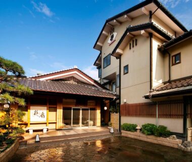 Traditional ryokan entrance courtyard with tiled roof and pine tree at Yuhigauraonsen ShizukaHanaogi Kyoto
