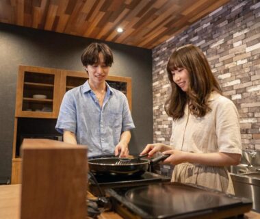 Two guests cooking at wooden counter with brick wall at YuiLocalZao Yamagata Tōhoku