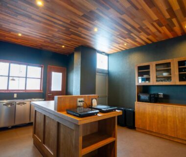 Communal kitchen with wooden ceiling, island and stainless steel sink at YuiLocalZao in Yamagata, Tōhoku, Japan