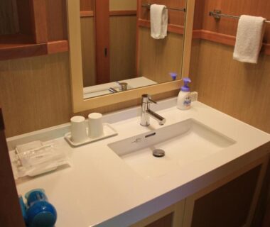 Rectangular sink and mirror with wooden walls, towels and toiletries at Yukaen in Iwate