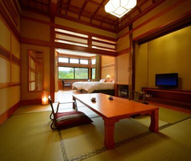 Tatami room with low table, zabuton seating, shoji screens and a bed at Yukaen in Iwate