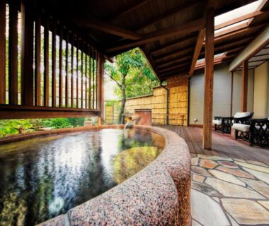 Covered stone onsen with wooden beams, lounge chairs and garden view at Yumeguri no Yado Yoshiharu Shizuoka