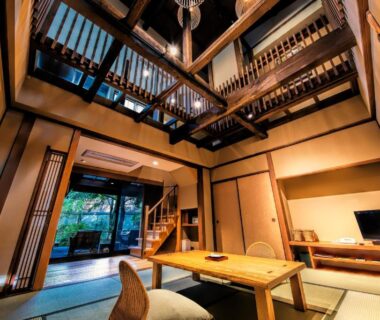 High-ceiling tatami room with low table and loft staircase at Yumeguri no Yado Yoshiharu in Shizuoka, Chūbu