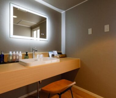 Illuminated mirror, wooden vanity with toiletries and stool in Yumenoi bathroom, Hyōgo, Kansai