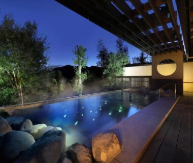 Outdoor onsen bath with stone edge and wooden deck at dusk, Yumenoi Hyōgo