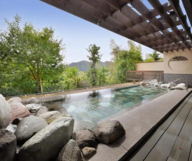 Stone-lined outdoor onsen with wooden deck at Yumenoian Yuyake Koyake in Hyōgo, Kansai