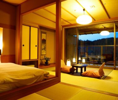 Tatami room with futon, low table, shoji screens and sliding doors opening to dusk garden view