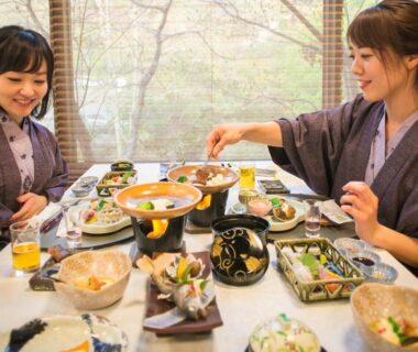Two guests in yukata sharing a multi-dish meal at Yumerindo ryokan table by window