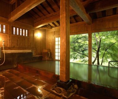 Indoor wooden onsen bath with shoji screens and garden view at Yumerindo Kumamoto