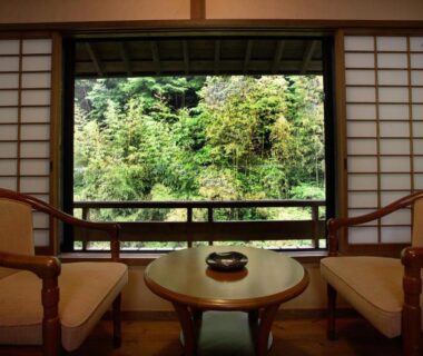 Two armchairs and low table by shoji screens overlooking lush forest at Yumerindo, Kumamoto