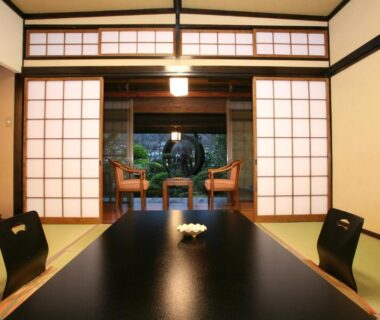 Traditional tatami room with low table, floor chairs, shoji screens opening to a framed garden view