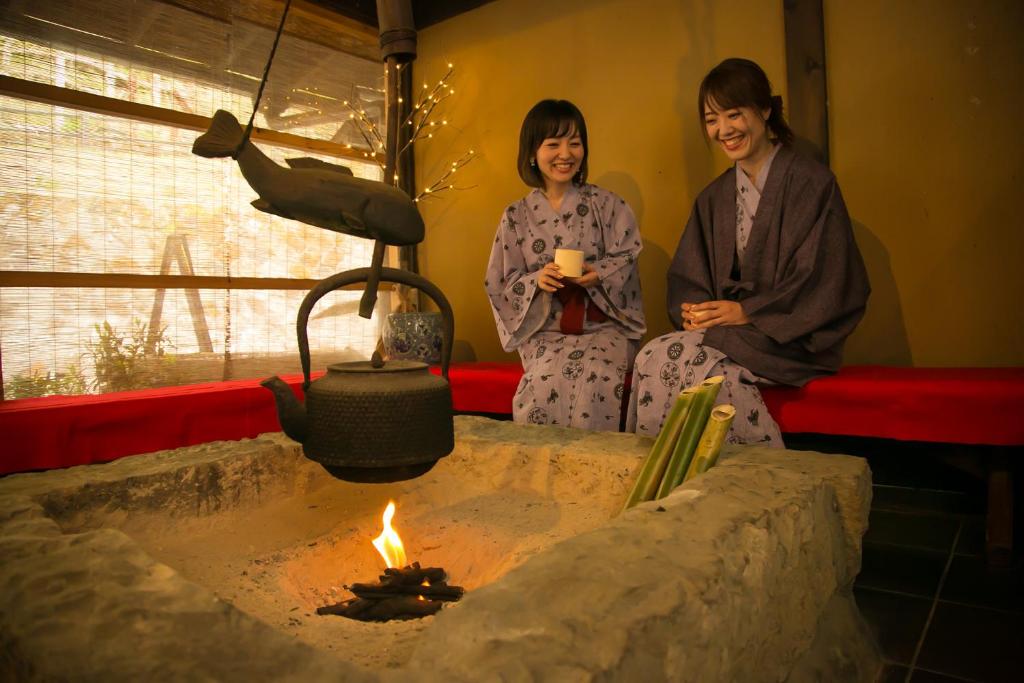 Guests in yukata by hearth Yumerindo Kumamoto Two guests in yukata at irori hearth with kettle, Yumerindo, Kumamoto, Kyūshū