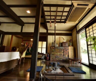 Traditional wooden common room with sunken hearth, shoji screens and zabuton cushions at Yumorinoyado Sannozyou, Yamagata
