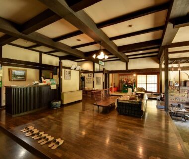 Traditional wooden lobby with reception desk, low tables, shoji screens and lined slippers at Yumorinoyado Sannozyou, Yamagata
