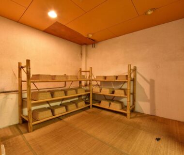 Tatami changing area with wooden shelves and storage baskets at Yumorinoyado Sannozyou Yamagata