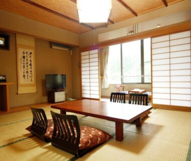 Tatami room with low wooden table, zabuton cushions, shoji screens and tokonoma at Yumoto Choseikan Gunma