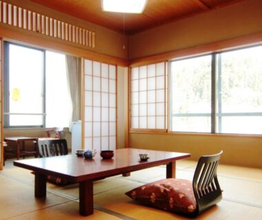 Traditional tatami room with low wooden table, floor cushions and shoji screens at Yumoto Choseikan in Gunma