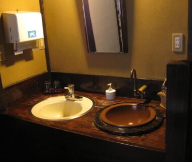 Bathroom counter with ceramic sink and wooden basin, mirror and soap dispenser at Yumoto Choza Gifu