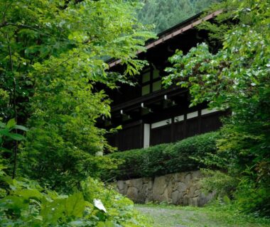 Wooden ryokan facade at Yumoto Choza surrounded by lush trees and stone wall in Gifu Chūbu Japan