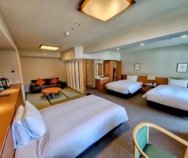 Room with three beds and tatami seating area, low table and sofa at Yumoto Fujiya Hotel, Kanagawa, Japan