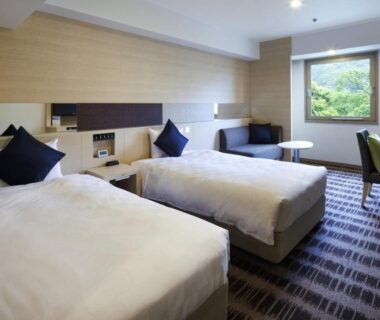Twin bedroom with sofa and window overlooking greenery at Yumoto Fujiya Hotel in Kanagawa, Kantō