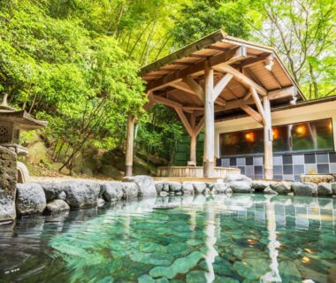 Stone outdoor onsen bath with wooden pavilion at Yumoto Fujiya Hotel in Kanagawa, Japan