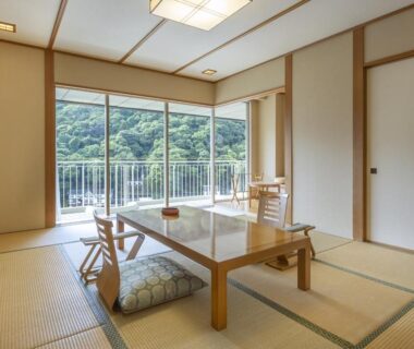 Traditional tatami room with low table, zabuton cushions and balcony overlooking wooded hills at Yumoto Fujiya Hotel, Kanagawa