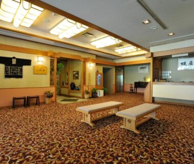 Carpeted ryokan lobby with low benches and wooden reception desk at Yumoto Itaya, Tochigi