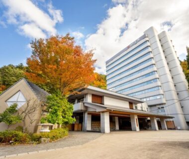 Modern guest tower and traditional entrance with maple tree in autumn at Yumoto Kissho, Miyagi, Tōhoku, Japan
