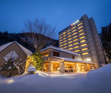 Evening view of lit multi-story ryokan and snow-covered entrance at Yumoto Kissho in Miyagi, Tōhoku