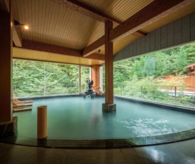 Large indoor onsen with wide windows overlooking forest at Yumoto Kissho in Miyagi Tōhoku
