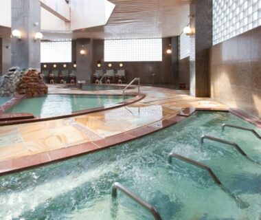 Spacious tiled indoor onsen with multiple baths, whirlpool jets, handrails and soft natural light at Yumoto Noboribetsu Hokkaidō