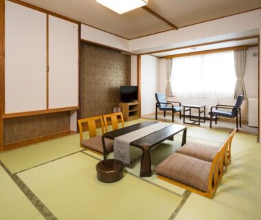 Tatami room with low table, floor chairs, sliding panels and window seating at Yumoto Noboribetsu Hokkaidō