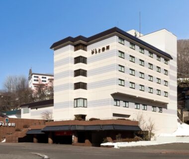 Multi-story ryokan building with striped facade and entrance canopy, set in a snowy Hokkaidō town near Noboribetsu