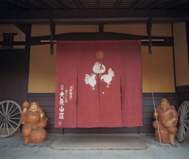 Red noren flanked by tanuki statues at Yumoto Onsen OharaSansou entrance in Kyoto, Kansai, Japan