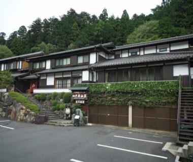 Multi-story wooden ryokan exterior with parking and hillside greenery at Yumoto Onsen OharaSansou Kyoto