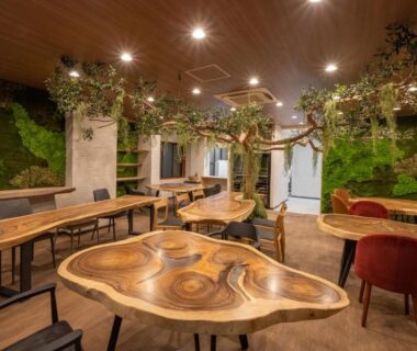 Communal lounge with live edge wooden tables, green plant walls, mixed seating at Yumura Onsen MIDORIYA, Hyōgo