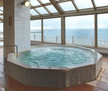 Tiled indoor hot spring bath next to large windows at Yunohama Hotel Hokkaidō
