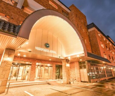 Warmly lit entrance canopy and driveway at dusk, Yunohama Hotel in Hokkaido