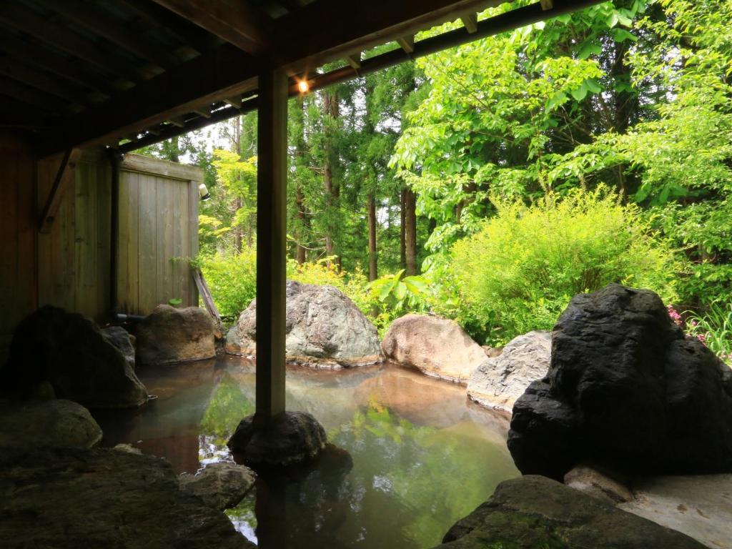 Rock-lined outdoor onsen Yunohirakan Gifu Covered rock bath with wooden roof and lush garden surroundings at Yunohirakan in Gifu