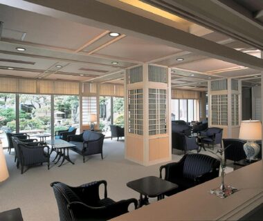 Ryokan lounge seating with armchairs and low tables facing a manicured garden at Yunokawa Kanko Hotel Shoen Hokkaidō
