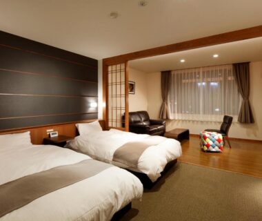 Two single beds, tatami seating area and shoji partition at Yunokawa Onsen Emi Hakodateya Hokkaidō