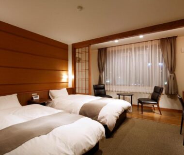 Relaxing twin bedroom with bedside lamps, seating area by window and shoji screen at Yunokawa Onsen Emi Hakodateya Hokkaidō