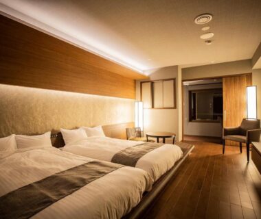 Spacious twin room with wooden floors, seating area and warm ambient lighting at Yunokawa Prince Hotel Nagisatei in Hokkaidō