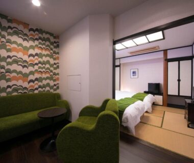 Traditional tatami sleeping area with futon beds and adjacent seating area with green sofa and patterned accent wall