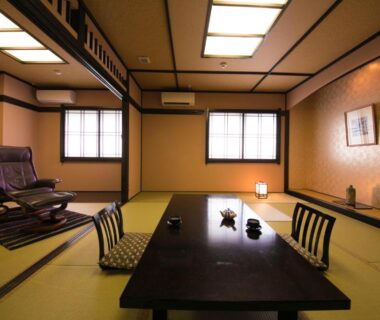 Traditional tatami room with low table, zaisu chairs, shoji windows at Yunosato Hayama, Ōita, Kyūshū, Japan