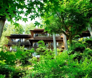 Traditional wooden ryokan building on a verdant hillside with balconies and mature trees in Gifu, Chūbu