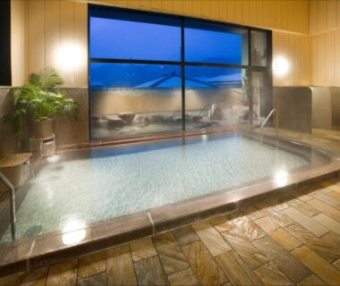 Steaming indoor onsen bath with tiled floor, wooden panelling and large window at Yura No Yado Seifuen, Nagano